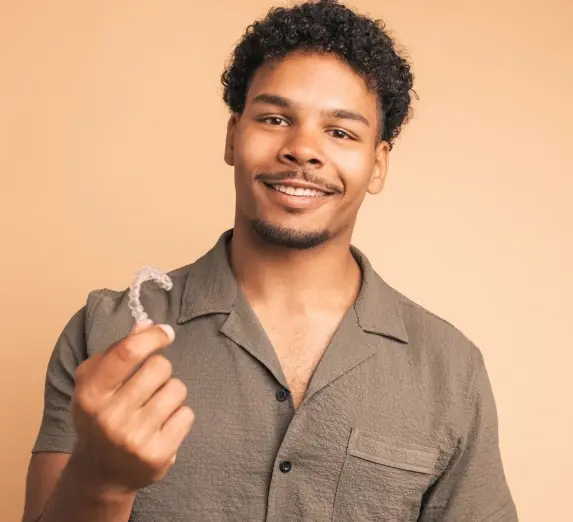 Smiling man holding dental floss in Williamson dental practice.
