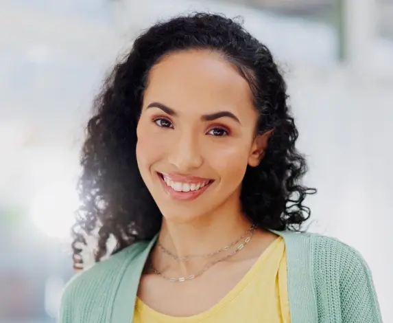 Smiling woman with bright teeth wearing yellow and green clothing in Williamson dental office.