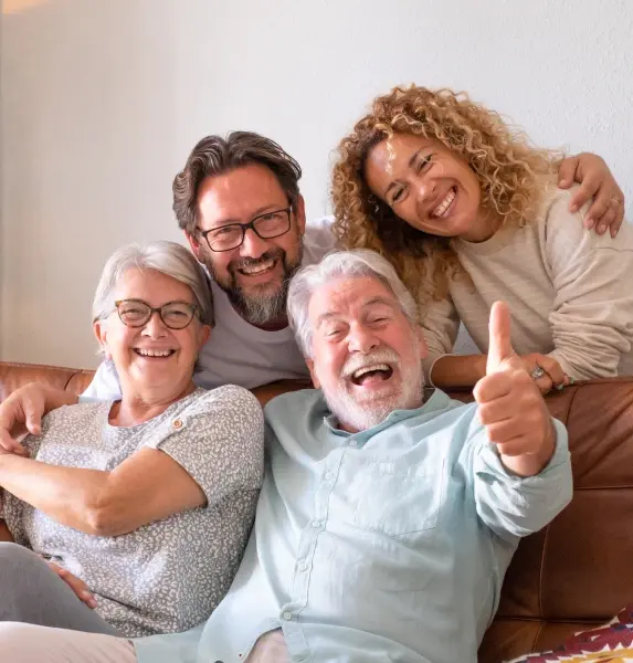 Happy multi-generational family smiling together on couch at dental practice in Williamson, WV.