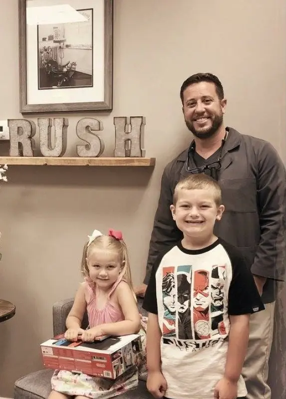 Dentist and two children smiling while holding Nintendo Switch prize at Williamson dental office.