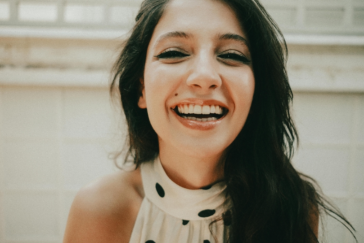 Young woman with a bright, genuine smile wearing a polka dot top.