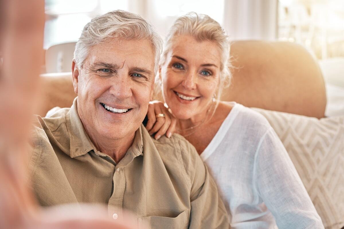 Happy senior couple smiling together during dental implant recovery consultation in Williamson.