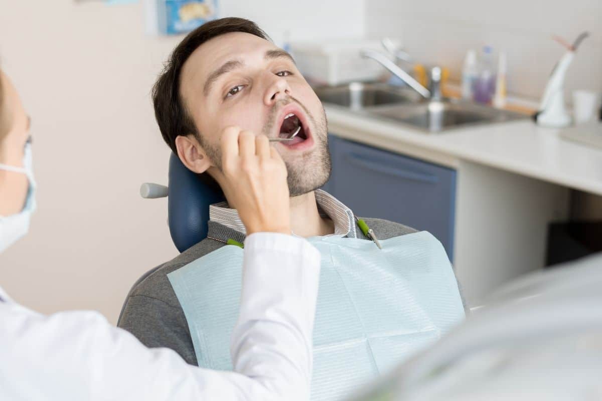 Patient in dental chair experiencing tooth pain during examination at Williamson dental practice.